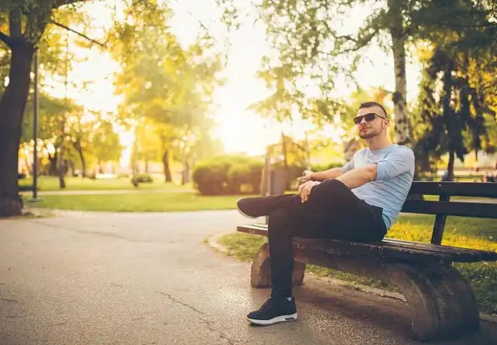Exhaling a long breath slowly on a park bench at dusk